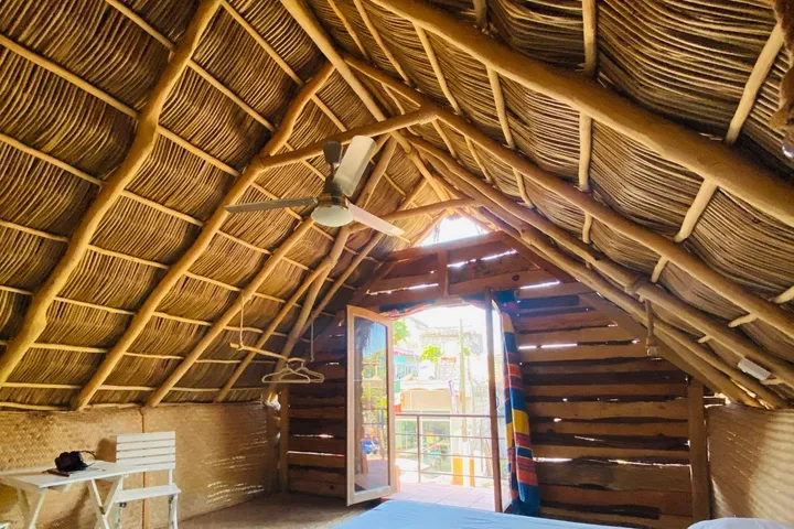 A queen bed under the palm thatch of the Brown Cabin